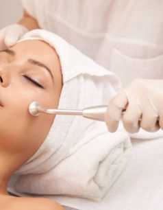 Cosmetologist using microdermabrasion machine for peeling, view from above